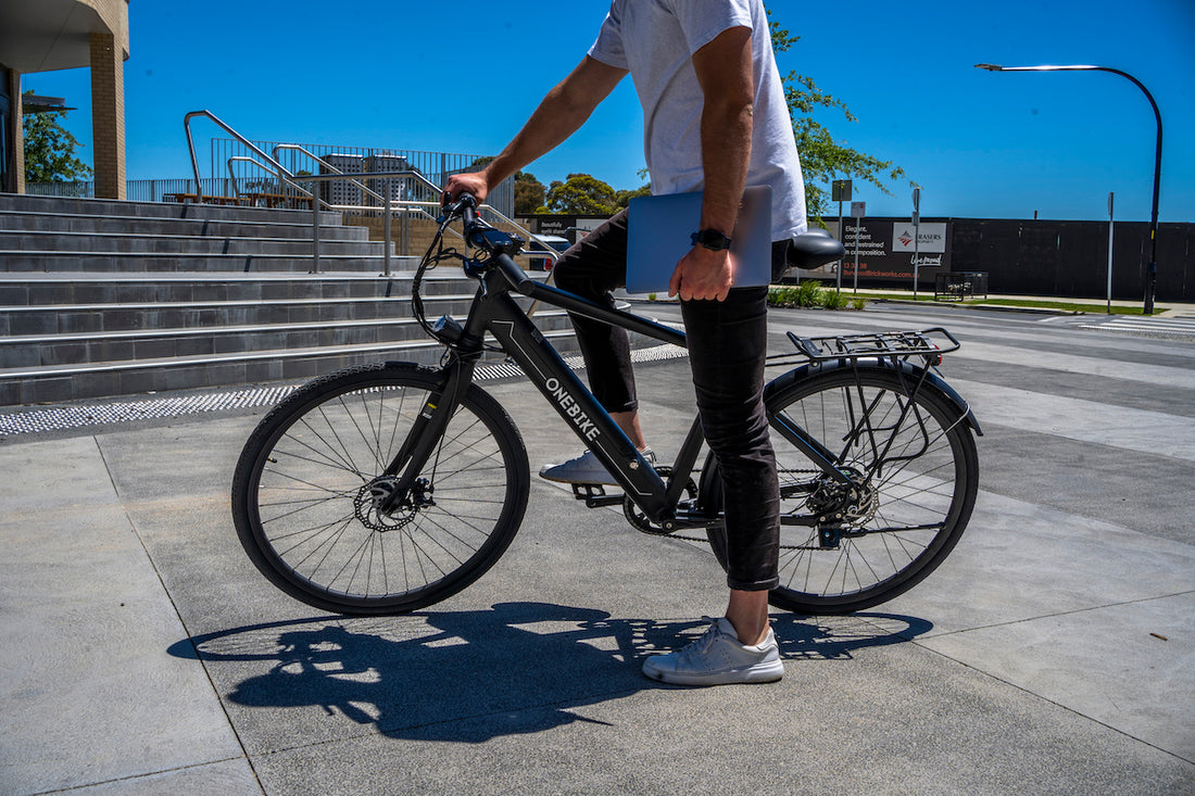 guy holding a laptop and on an electric bike